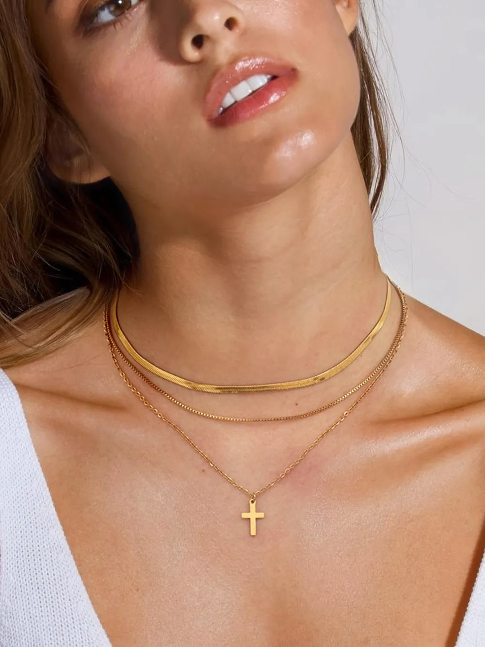 Trendy layered look featuring an 18k gold plated cross necklace and bold gold choker