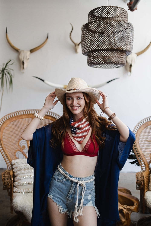 Woman wearing a boho outback hat with a red bikini and denim shorts in a styled interior
