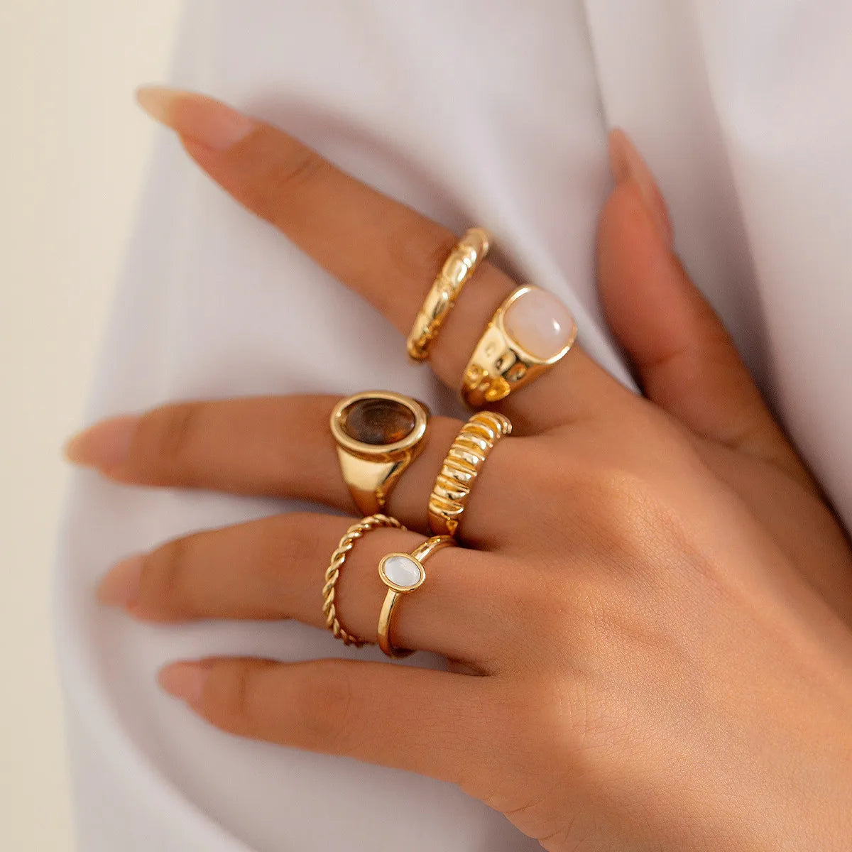 Collection of handcrafted gold stainless steel rings styled on a model's hand for trendy fashion